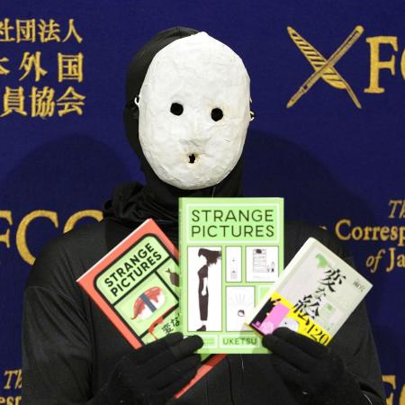 <p>　記者会見で著書を手にする覆面作家の雨穴さん＝２０２５年１月、東京都千代田区の日本外国特派員協会</p>