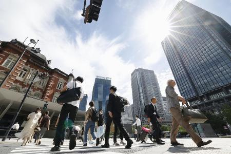 <p>　強い日差しの中、ＪＲ東京駅前を歩く人たち</p>