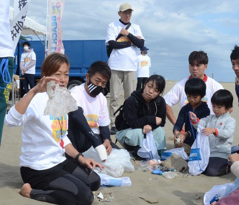 砂浜で拾ったビニールごみを「亀などの動物が間違って食べてしまうこともある」と紹介する遊佐さん（左）＝九十九里町
