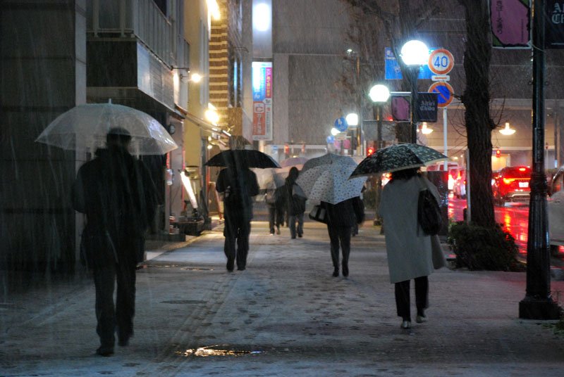 雪が積もる中、傘を差して駅に向かう人たち＝５日午後５時４５分ごろ、千葉市中央区
