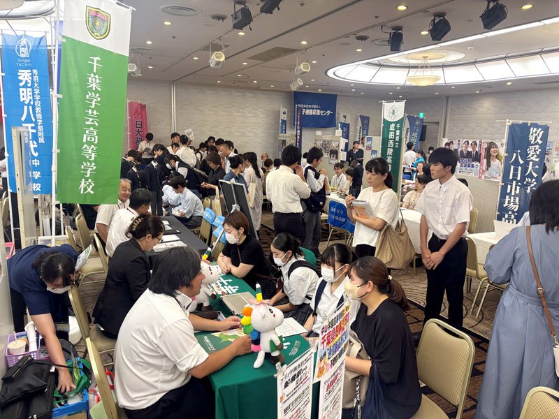 学校のブースで受験相談する来場者ら＝２４日、成田市