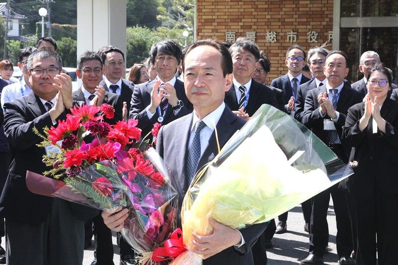 職員と市民らの拍手を受けながら市役所を後にする石井氏＝２２日、南房総市
